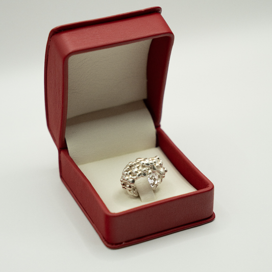 Silver ring in a red jewelry box on a white background