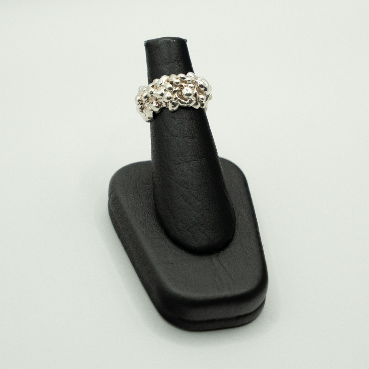 Silver ring on a black ring holder against a white background