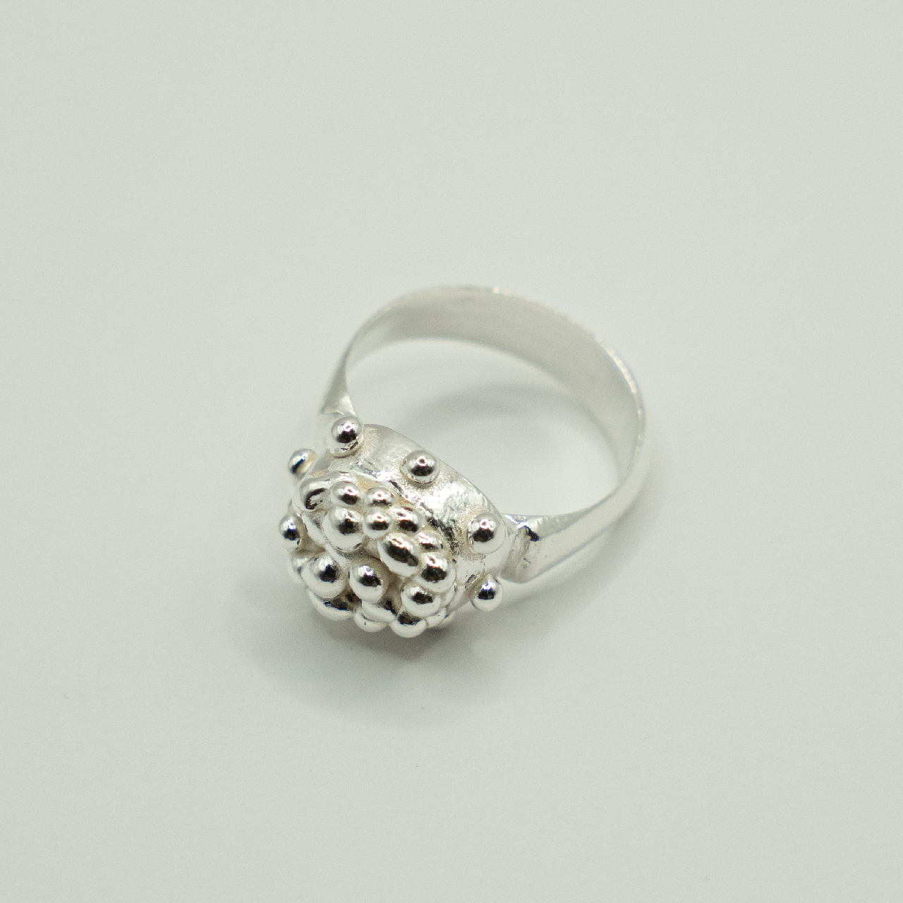 Silver ring with textured design on a light gray background
