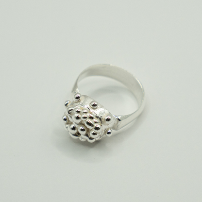 Silver ring with textured design on a light gray background